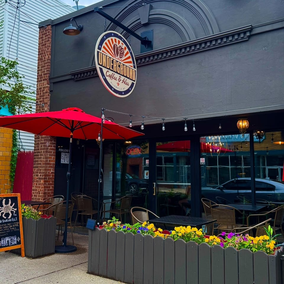 Exterior of Underground Coffee & Ales with outdoor seating, red umbrellas, and flower boxes.